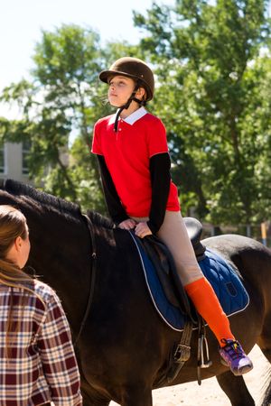 Rider on horse receiving instruction in sunlight.