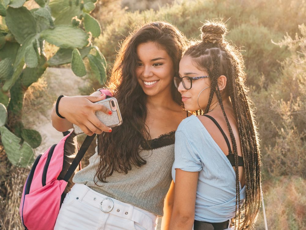 Smiling trendy young women taking selfie at countryside