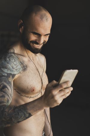 Cheerful sportsman using smartphone in gym