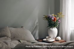 Cup of coffee, pumpkin on retro wooden bedside table, bouquet of dahlia, cosmos, solidago flowers, beige muslin cushions, book in bed near window 4A1Nq4