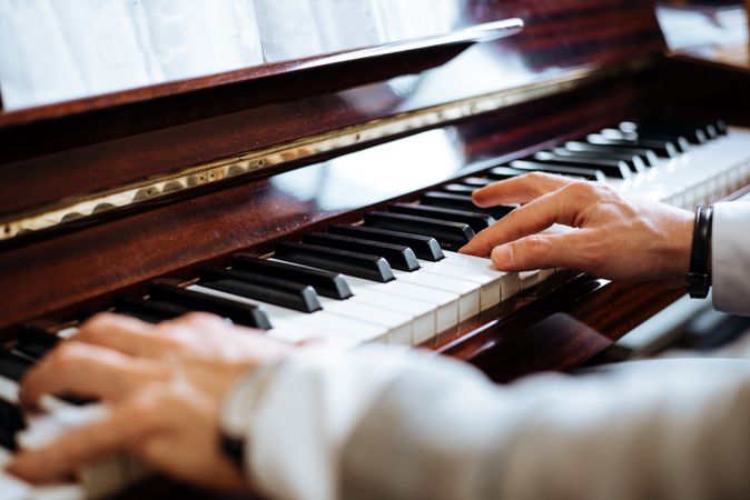 Crop male hands playing piano
