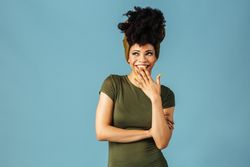 Studio shoot of Black woman smiling with hand over mouth