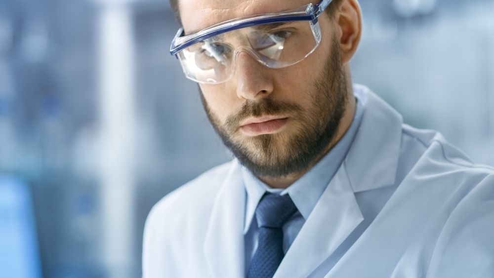 Close-up Face Shot of Scientist working and looking into Camera in a Modern Laboratory.