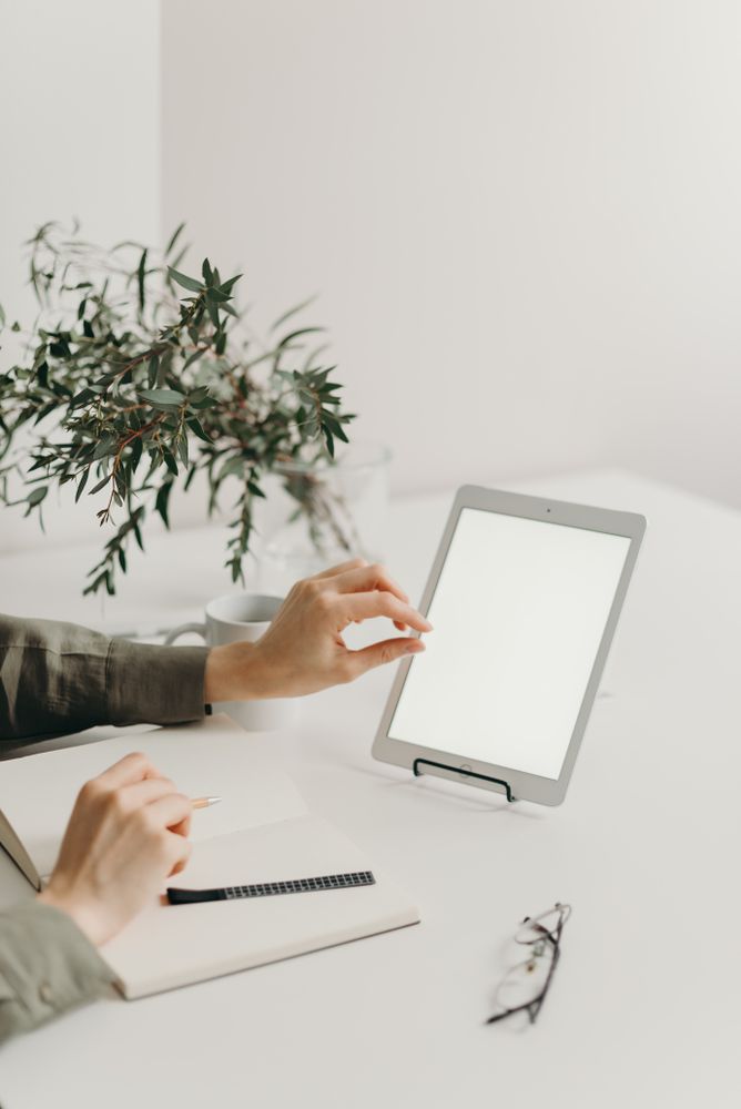 Cropped image of a person using tablet computer on light desk