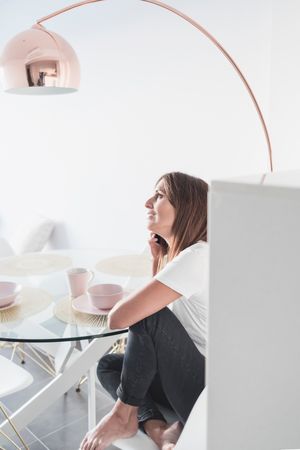 Smiling female sitting at sunny breakfast table talking on phone in front of cereal bowl