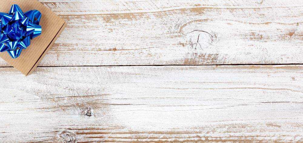 Gift box in left upper corner for the holiday seasons on rustic wood with plenty of copy space