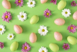 Flowers, green and brown eggs on pastel pink background
