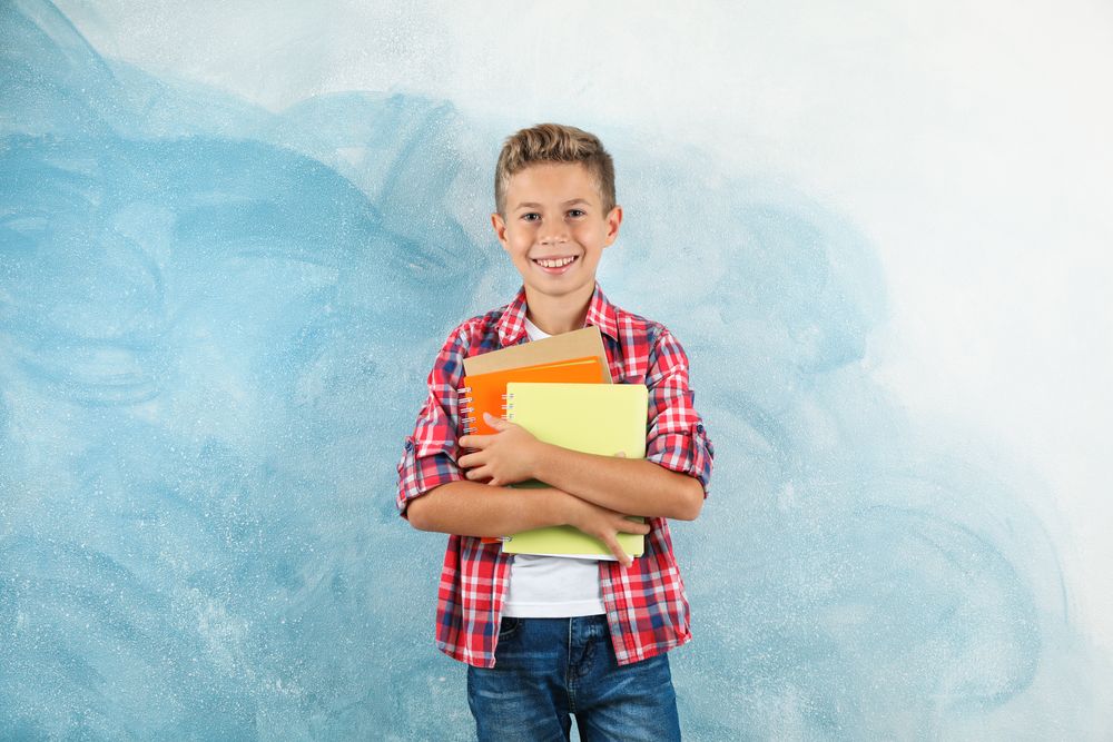 Boy with copybooks against color background, space for text