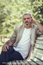 Portrait of a grey haired man, sitting on bench in a park 4d6pn0