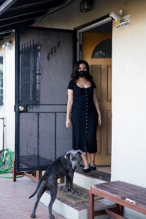 Woman standing at front door looking at camera with her dog