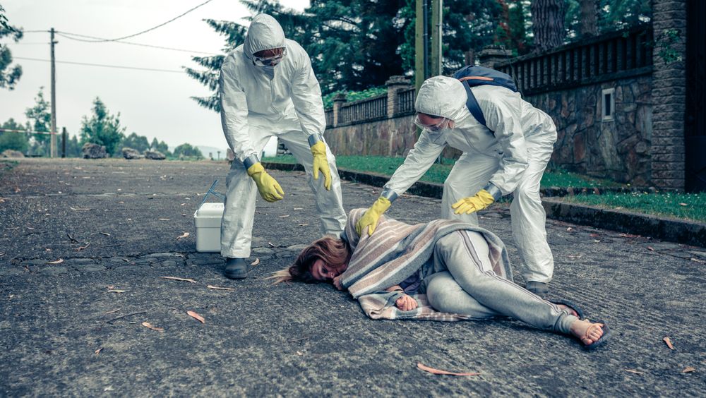 Doctors in protection suits caring for a woman
