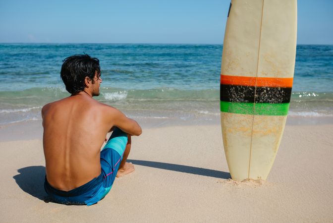 Male surfer relaxing on the sea shore