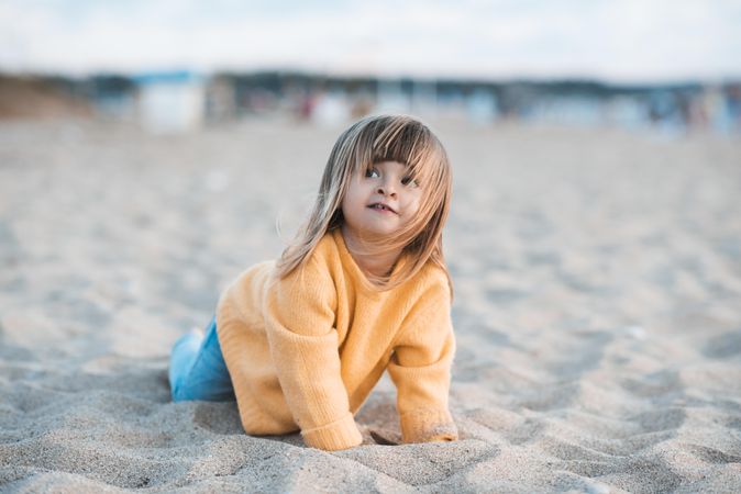 Girl in yellow sweater playing at beach