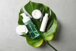 Flat lay with body care accessories and palm leaf on grey background, copy space