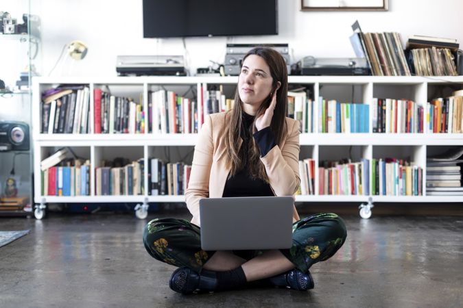 Portrait of a smiling woman sitting cross legged working on laptop