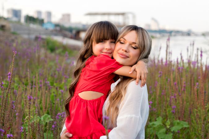 Mom and little daughter walking among meadow flowers