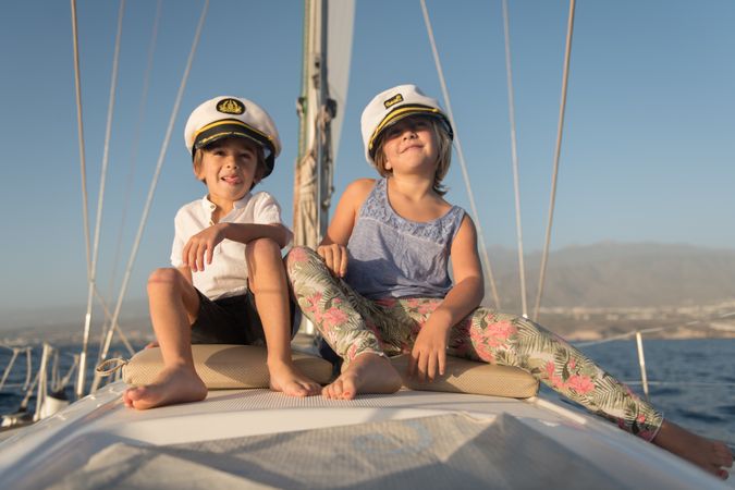 Smiling children sitting on deck of yacht in sea
