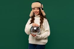 Smiling girl in winter hat holding small disco ball.