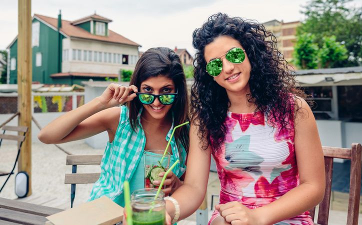 Female friends in sunglasses sitting outside