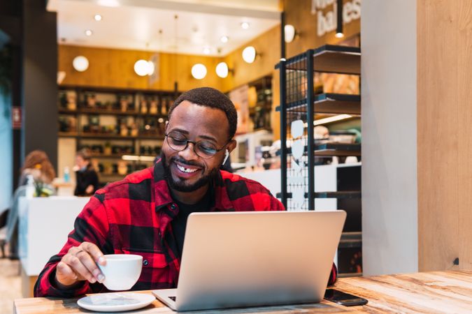 Smiling Black man working on laptop in cafe