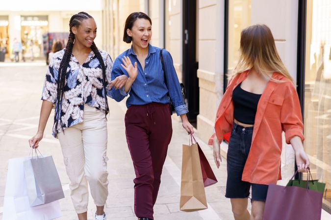 Women greeting each other on street with shopping bags