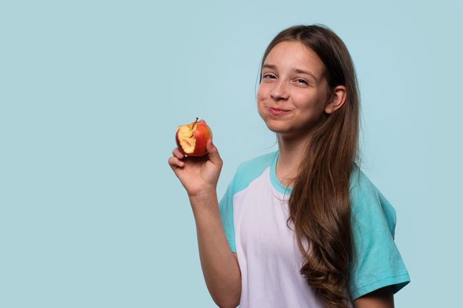 Girl smiles mischievously while holding an apple