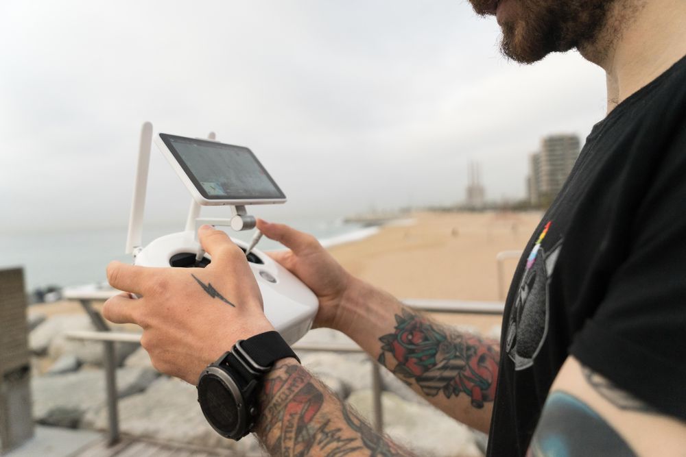 Sideview of man with remote for drone on wooden boardwalk on beach