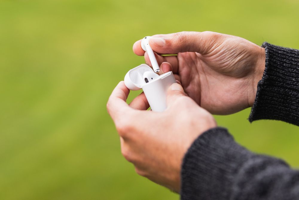 Crop man with earbuds in case against green background