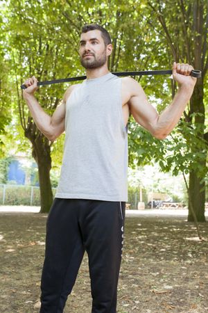 Sportsman stretching and resting with rubber in park
