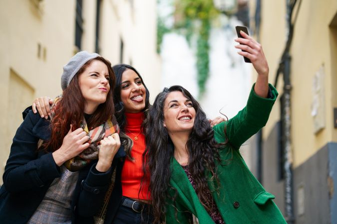 Female friends dressed in fall clothes pose for selfie