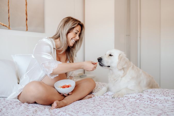 Pregnant woman eating fruits and resting with dog