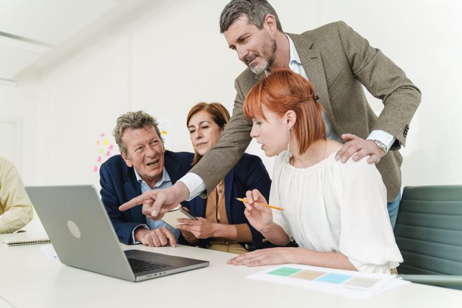 Three colleagues engage in a collaborative discussion, intently observing a laptop focused on design project