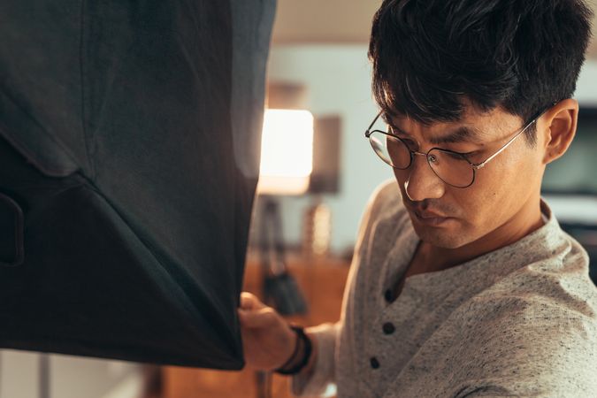 Asian male photographer adjusting lighting equipment