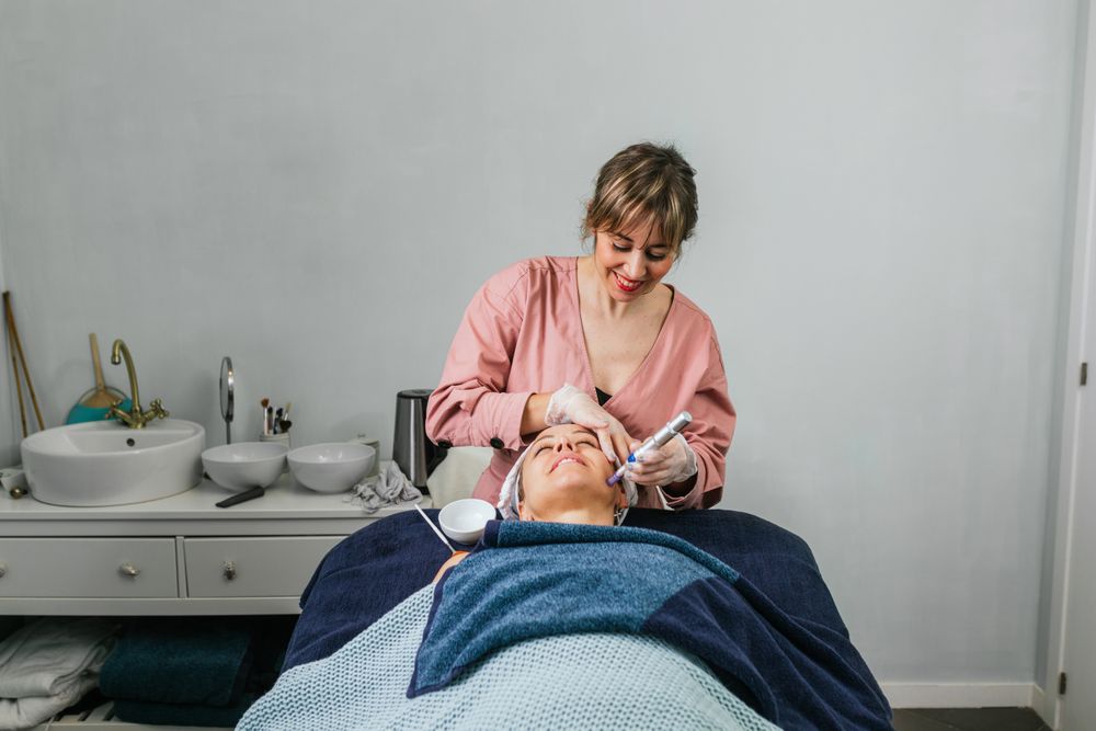 Cosmetologist doing microdermabrasion procedure of face of client