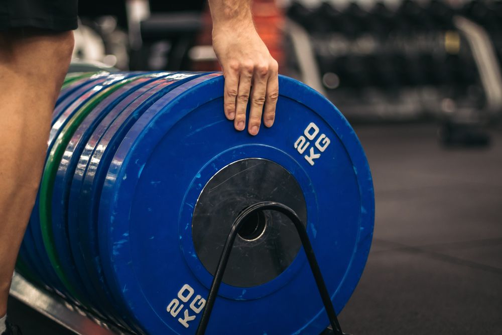 man taking a weight plate in a gym