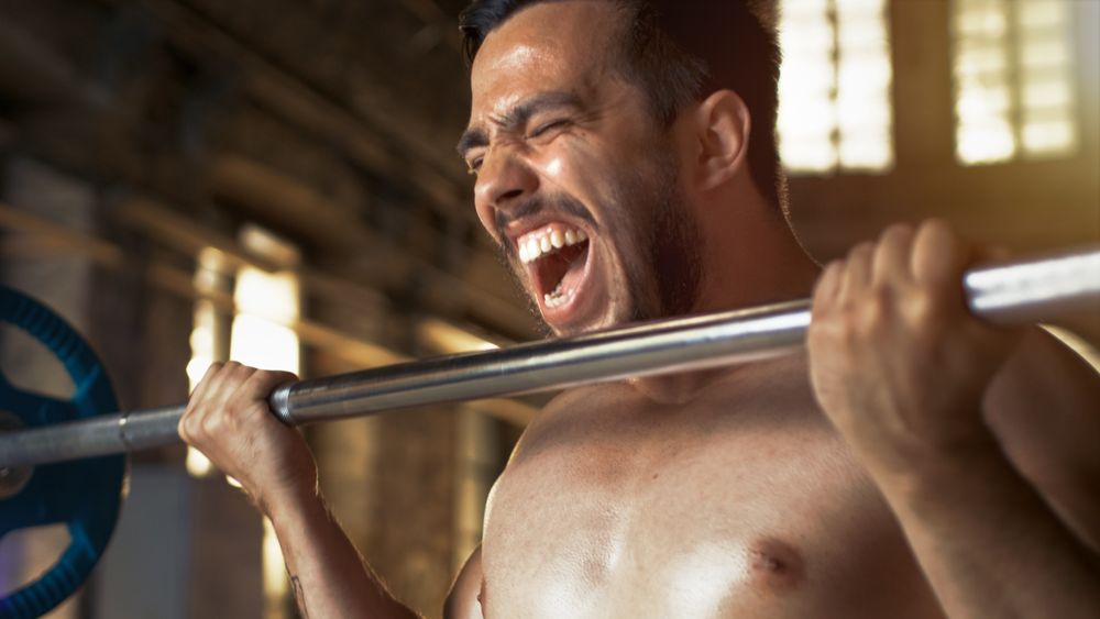 Muscular Shirtless Man Lifting Heavy Barbell with Effort