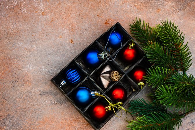 Top view of box of Christmas baubles with fir
