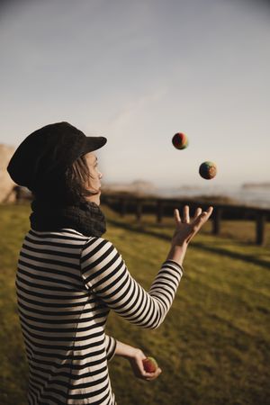 Woman juggling balls on meadow on shore