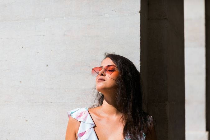 Dreamy stylish woman in sunglasses standing on city street