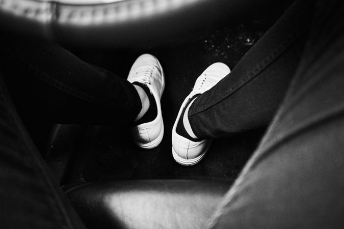 Grayscale photo of person's feet in light shoes