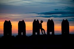 Silhouette of person between stone sculptures in sunset