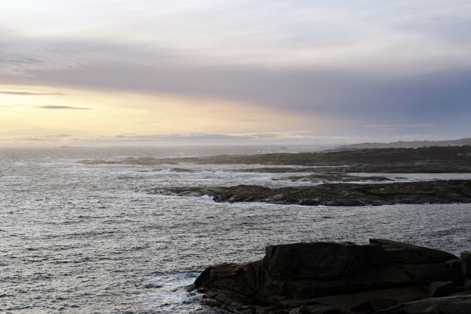 Rocky seashore and dark wavy sea in dusk