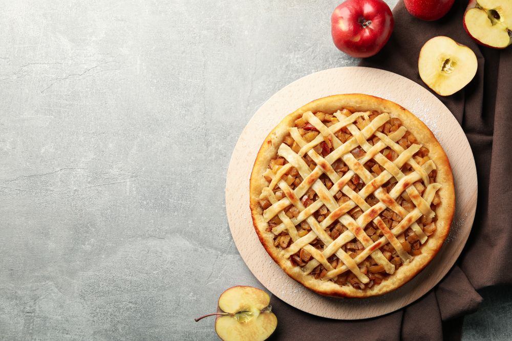 Composition with apple pie and ingredients on gray background, top view