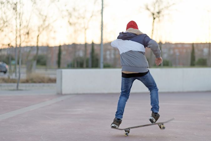 Back of young man riding on skateboard in street