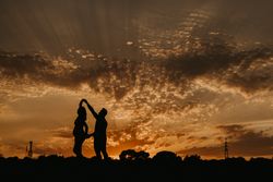 Anonymous couple dancing during sunset