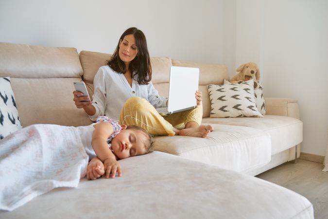 Mother working remotely near sleeping daughter at home