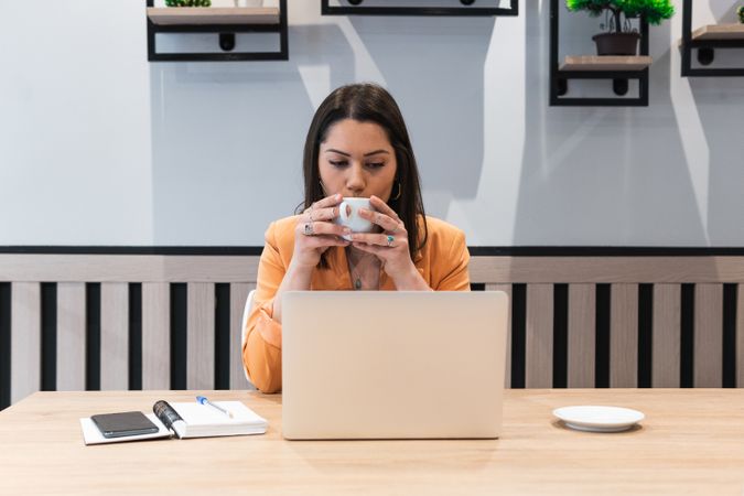 Woman working in cafe and drinking coffee