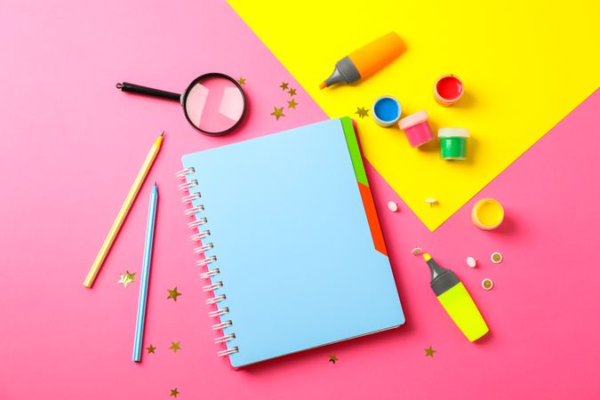 Flat lay composition with school supplies on two tone background, space for text