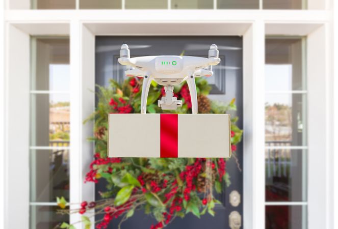 Drone Delivering Wrapped Package with Red Ribbon to Christmas Decorated House Porch