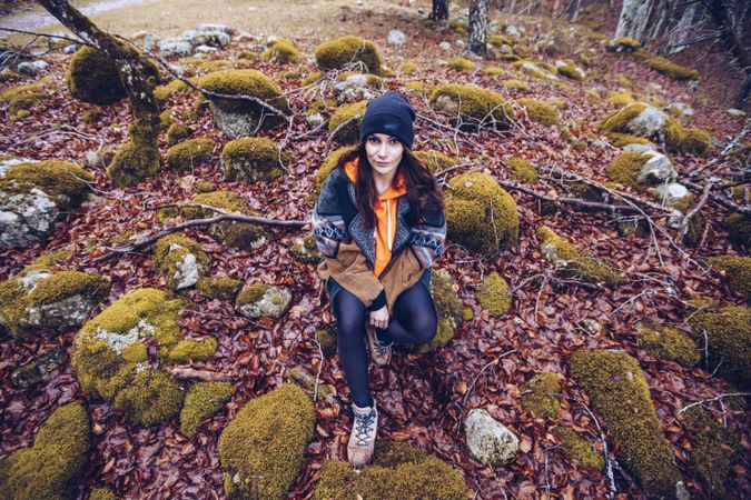 Bored female tourist resting on rock at autumn forest